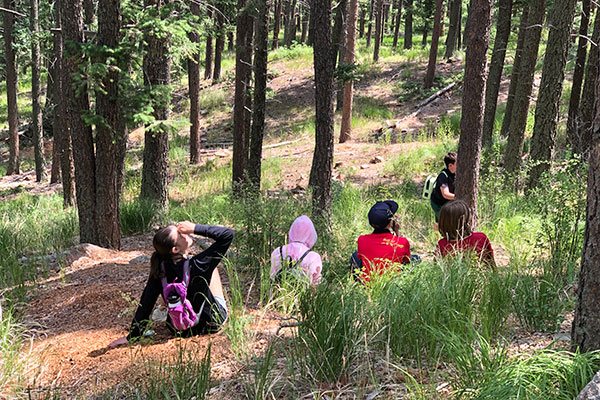 Teens in the forest on a walk with Cheyenne Mountain Zoo teen program